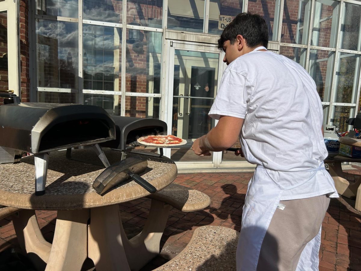 Mr. Tuti turning a pizza to ensure even browning.