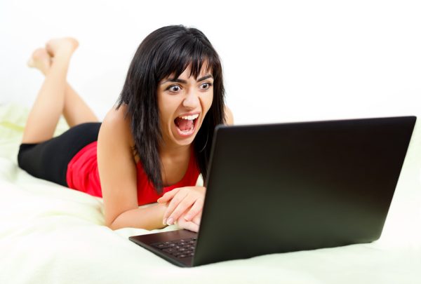 Young stressed woman yelling in the front of her laptop.